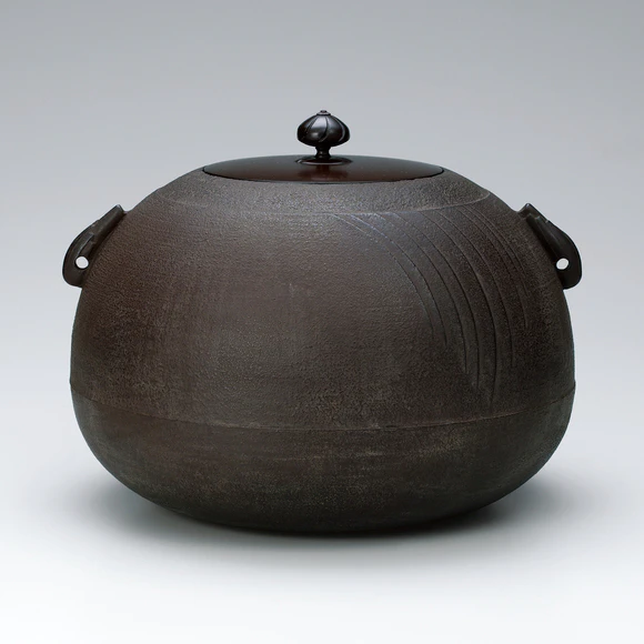 Tea ceremony kettle in shape of sacred jewel with raised line decoration.