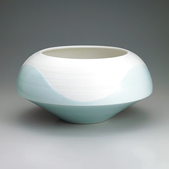 White porcelain bowl with pale blue glaze and line design.