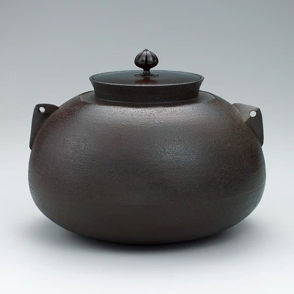 Tea ceremony kettle with jūōguchi and sloping shoulder.