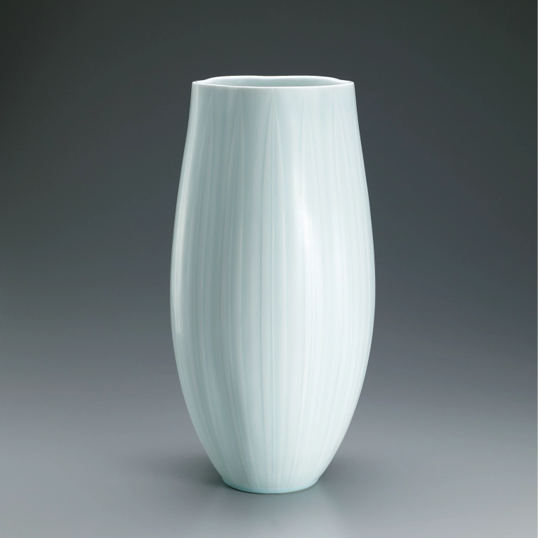 photo White porcelain flower vessel with pale blue glaze and line design.