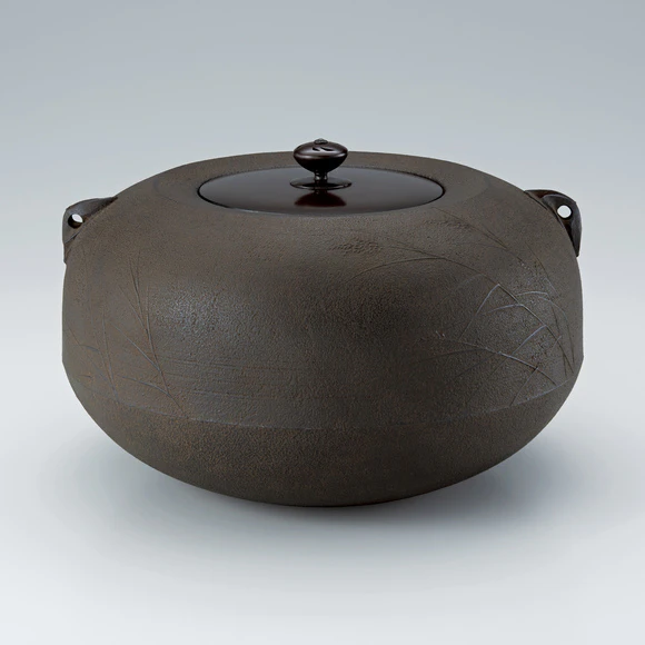 Tea ceremony kettle with caved-in mouth and reedy waterside design.