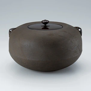 Tea ceremony kettle with caved-in mouth and reedy waterside design.
