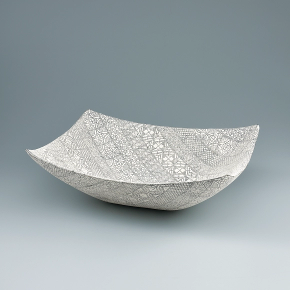 Square vessel with bands of different patterns in cut paper stencil.