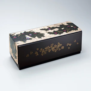 Box with design in makie on plain wood surface. “Spring plants”