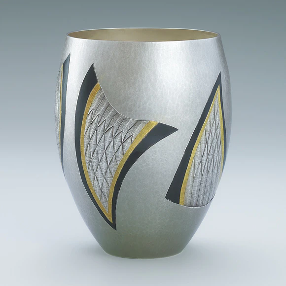 Silver flower vessel with shakudō inlay and carved decoration.