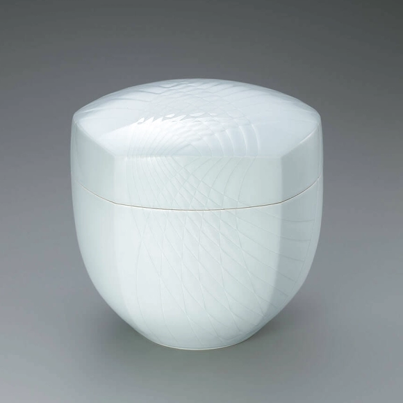 White porcelain covered vessel with pale blue glaze and engraved irregular ajiro weave pattern.