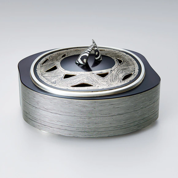Layered metal incense burner with wave design.