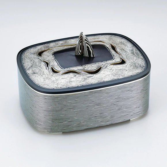 Layered metal incense burner with wave design.