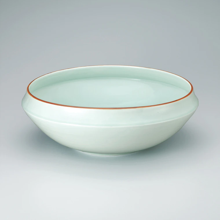 photo White porcelain bowl with pale blue glaze and red rim
