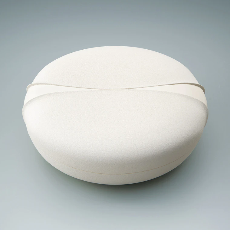 photo White porcelain round box with sprayed slip decoration.