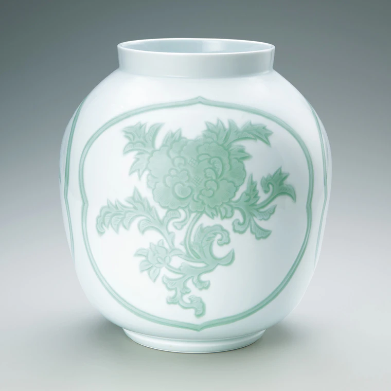 photo White porcelain jar with engraved and green glazed design of peony.