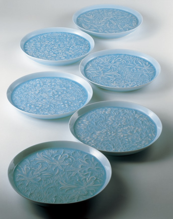 photo White Porcelain Set of Dishes with Pale Blue Glaze and Flowering Plant Design
